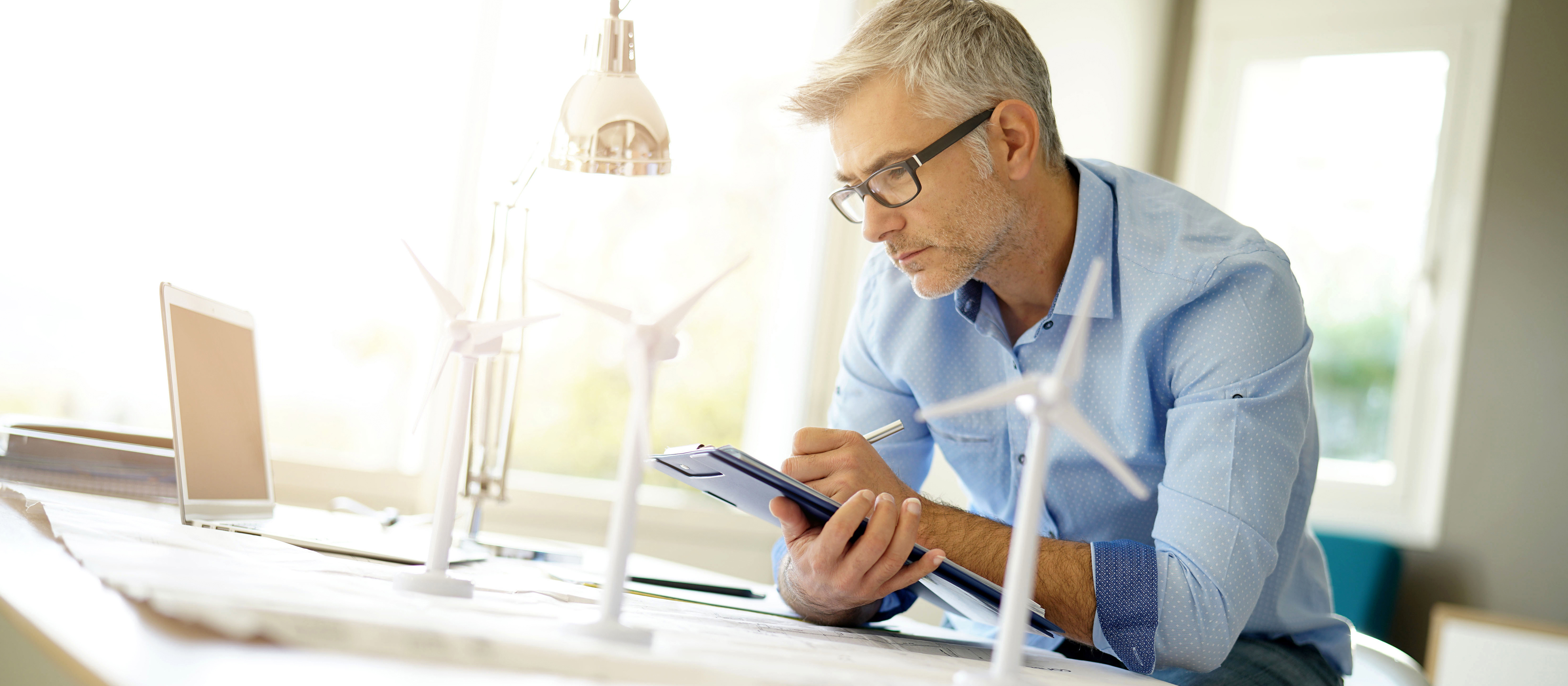 man standing at a desk writing on a tablet 