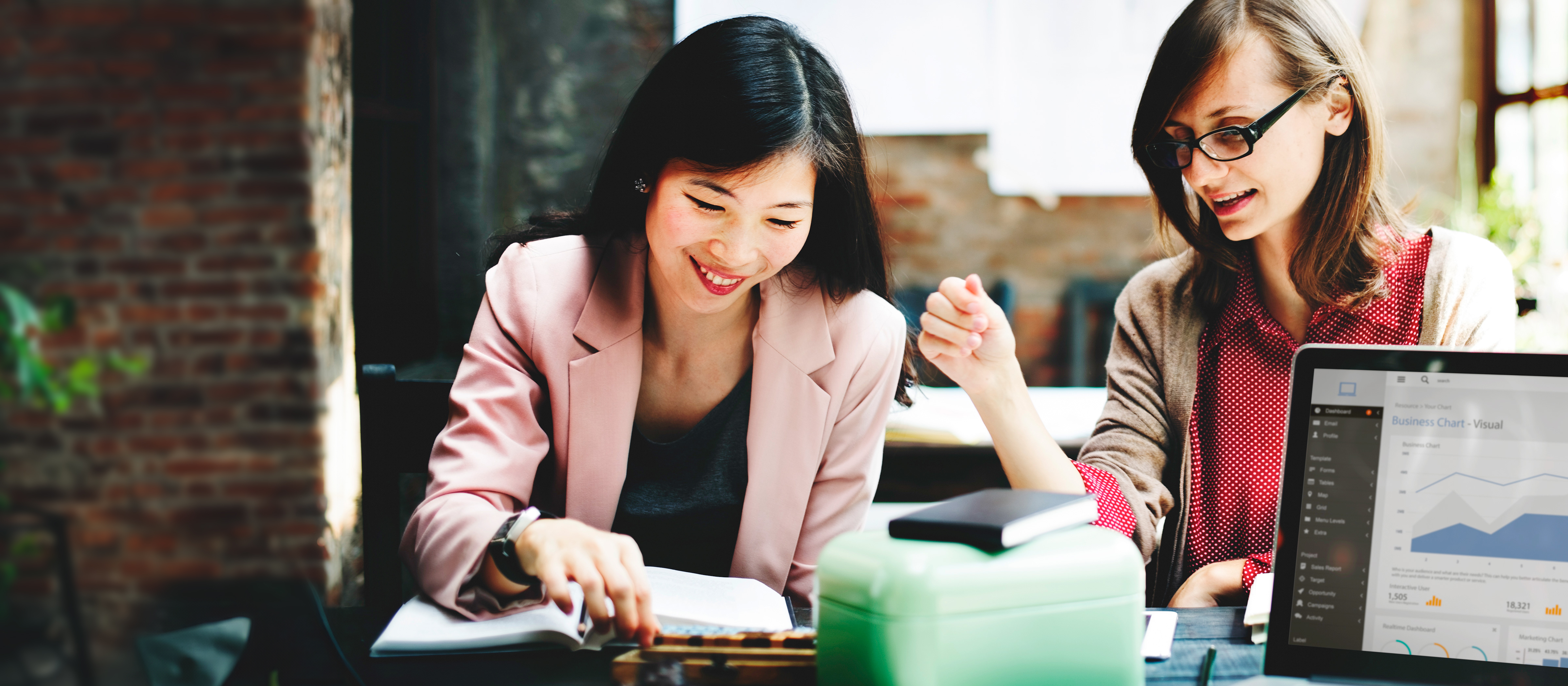 two people speaking to each other while sitting at a desk