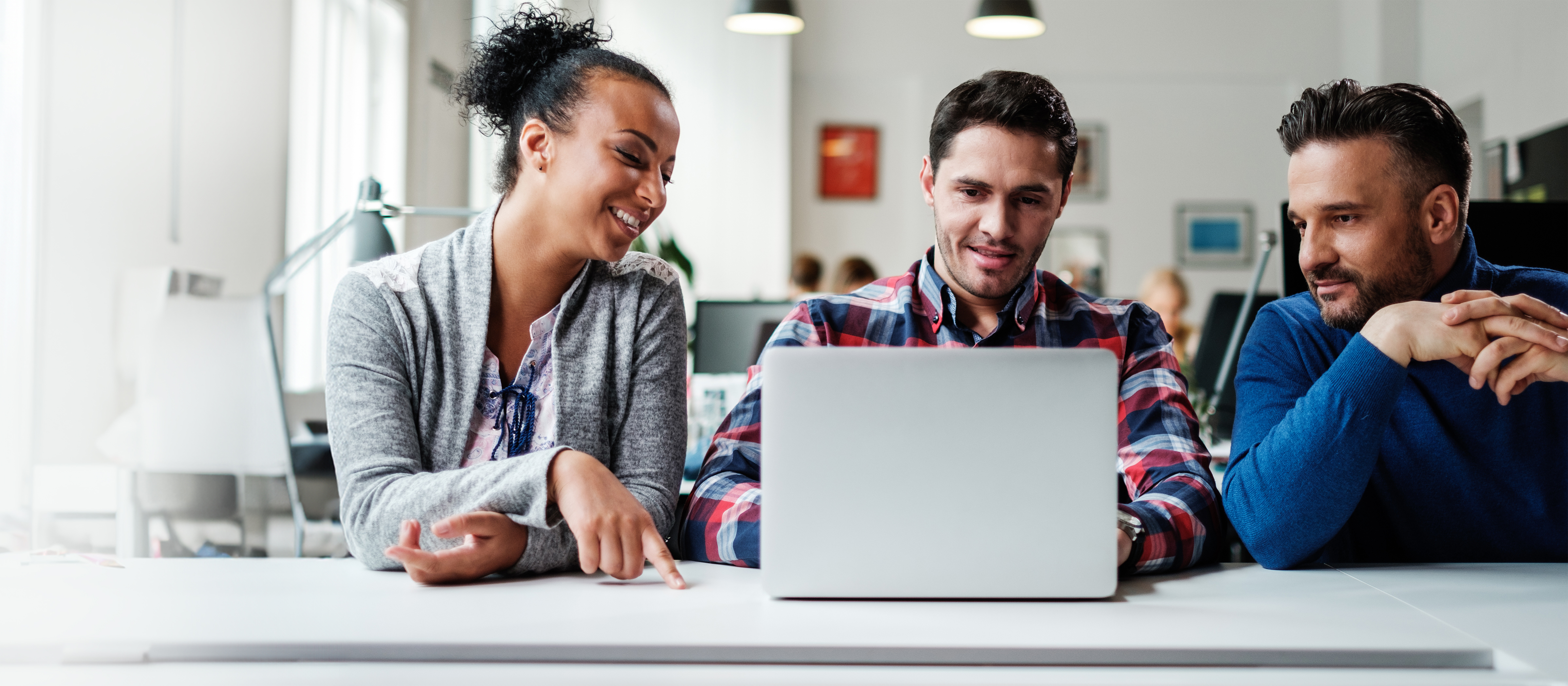 coworkers look at a laptop in an office setting