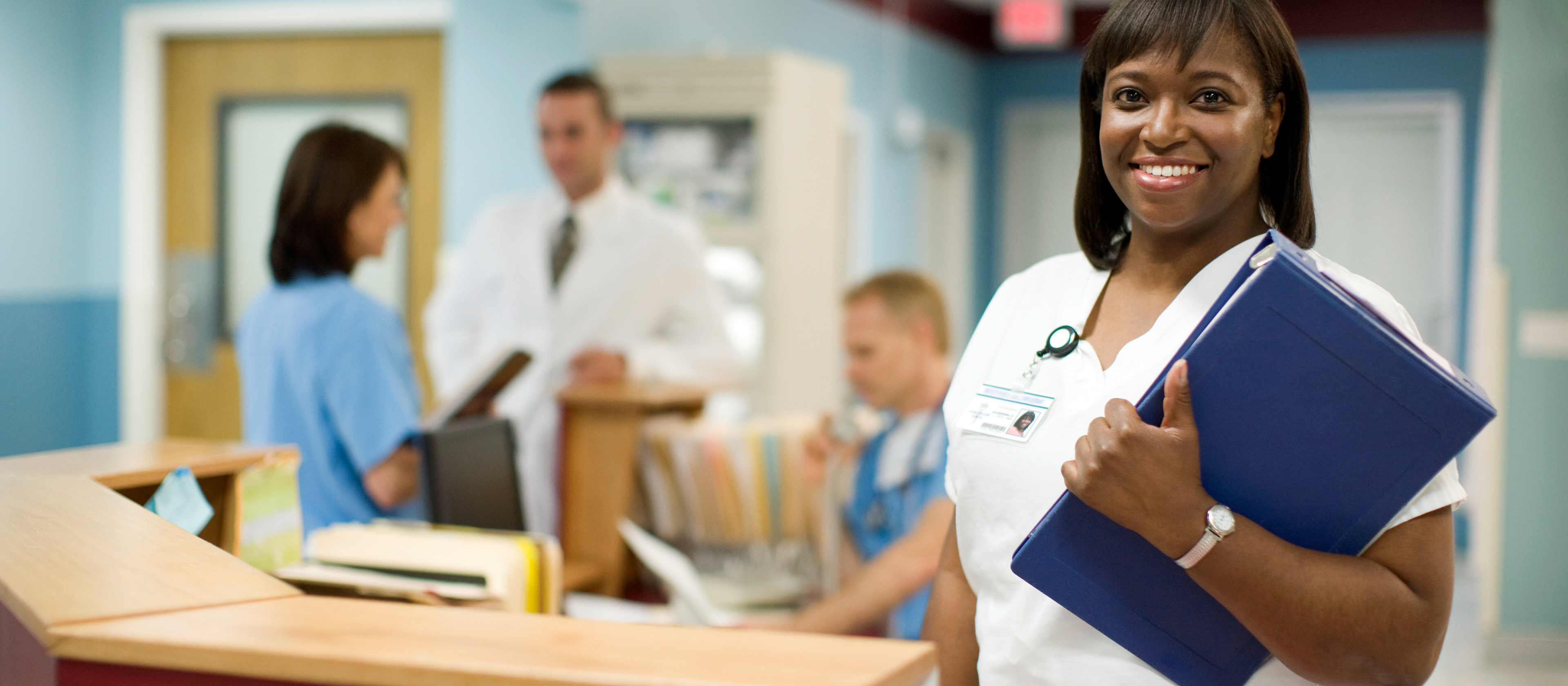 doctor smiling in front of a desk in a hospital 