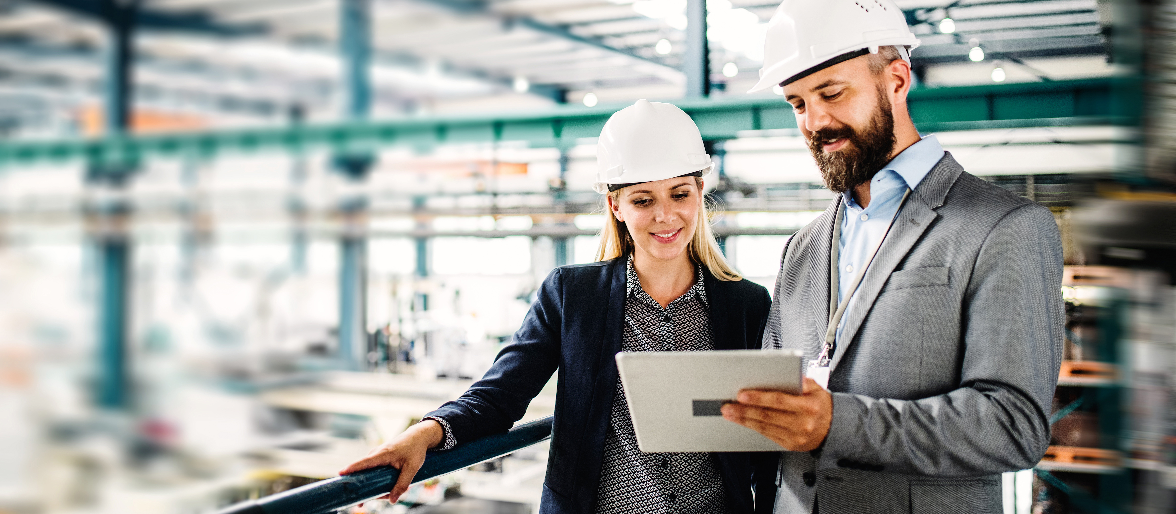 engineers wearing hard hats and looking at a tablet at a job site