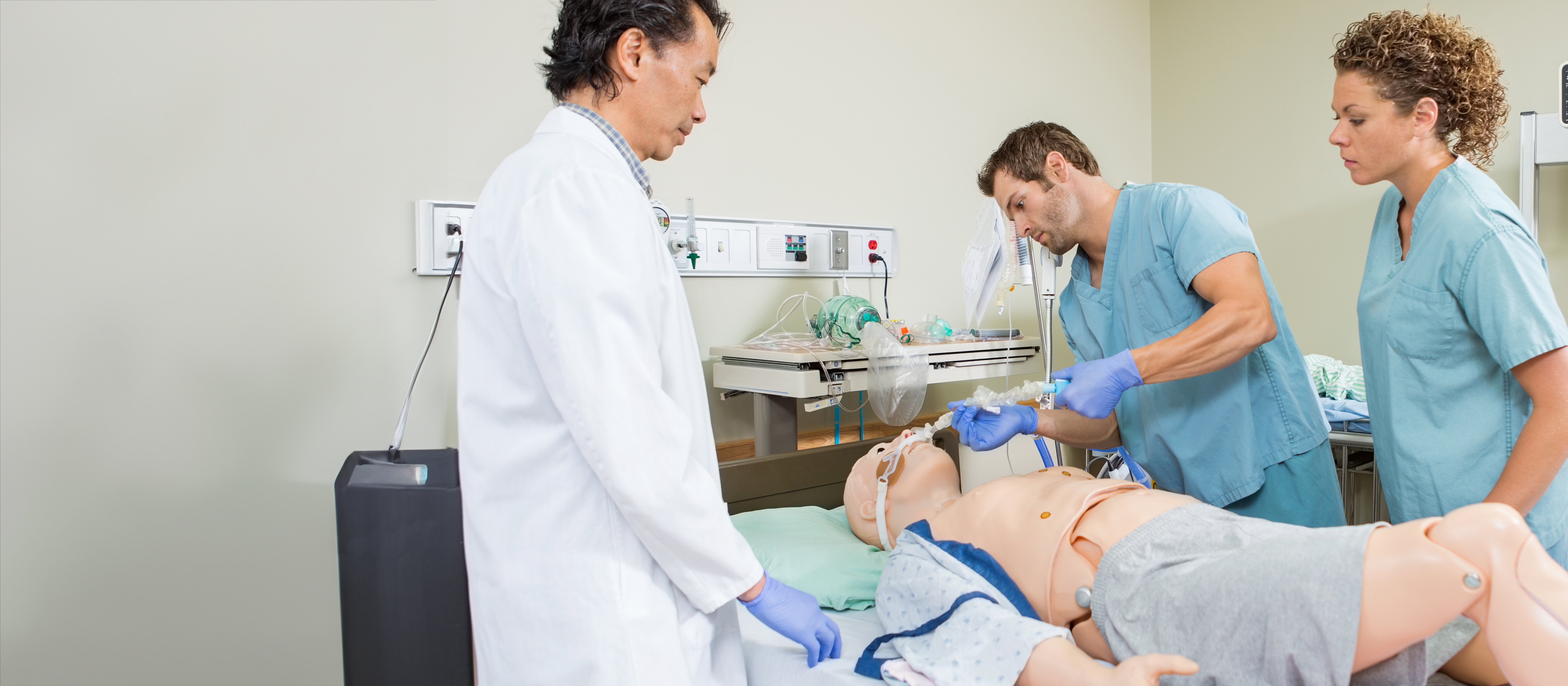 nursing students caring for a patient manikin while a doctor supervises