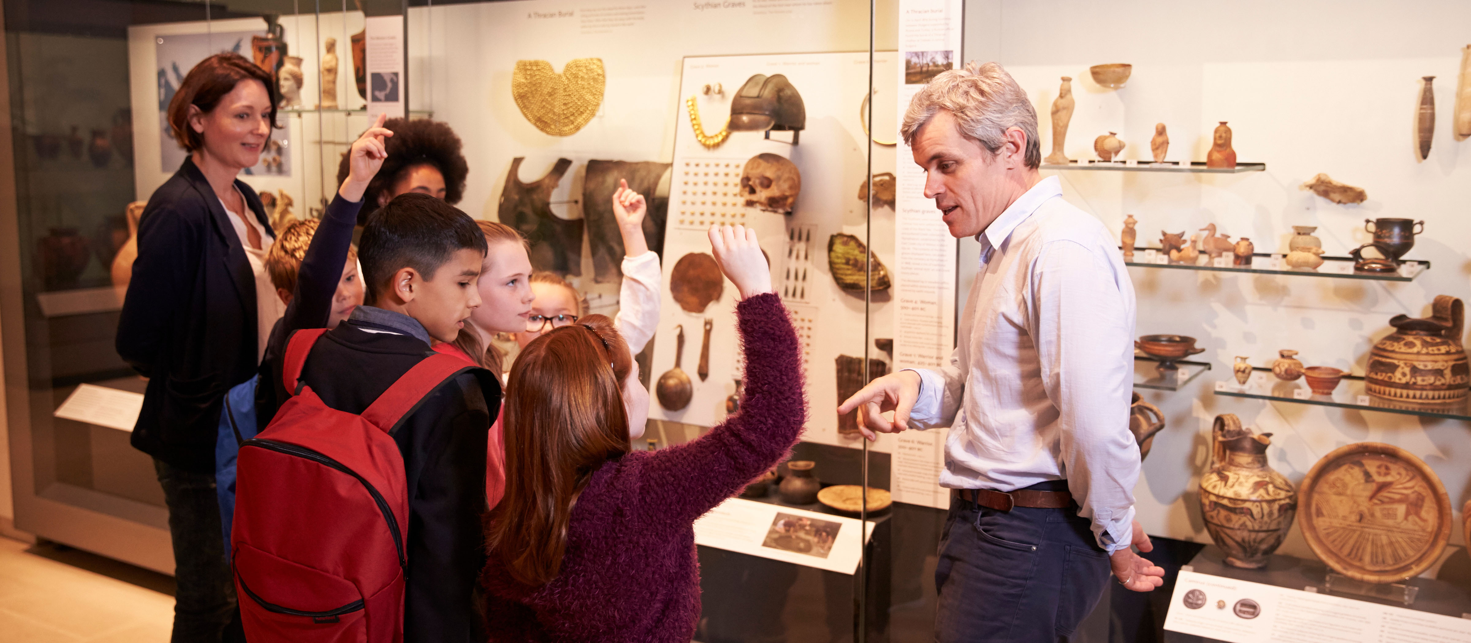 Historian explaining exhibit and artifacts to students at a museum