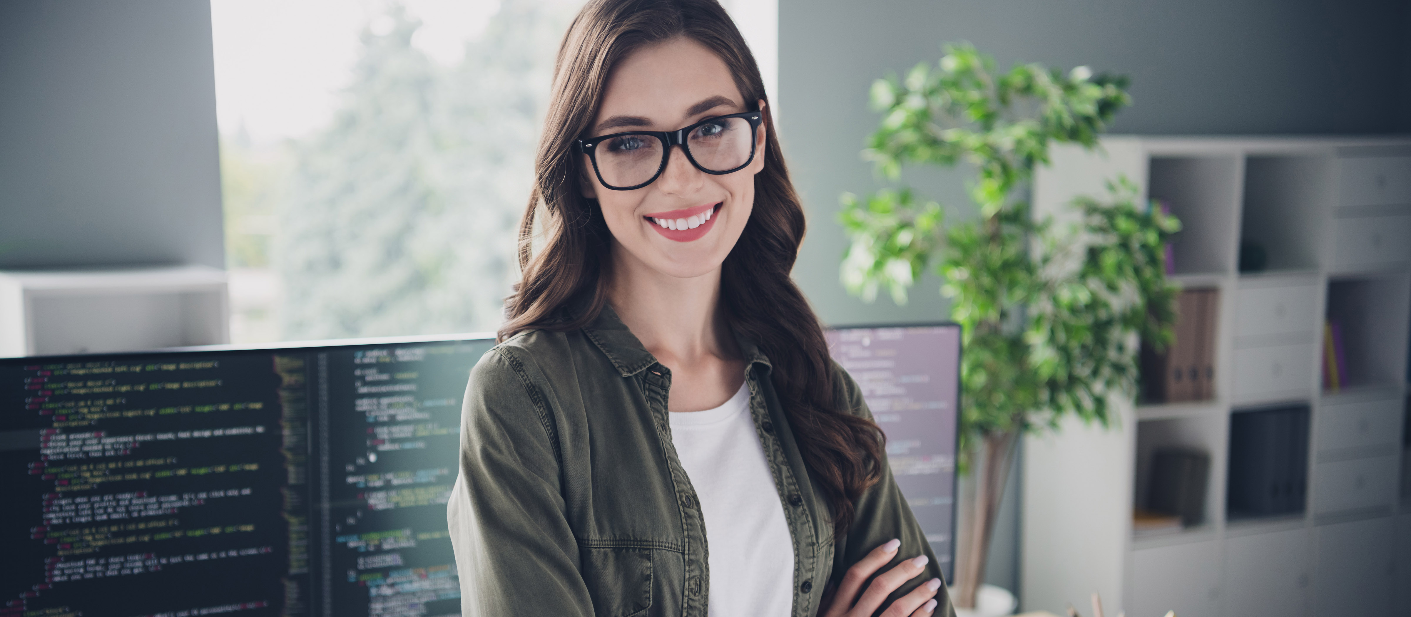 woman standing in front of a computer, smiling at the camera