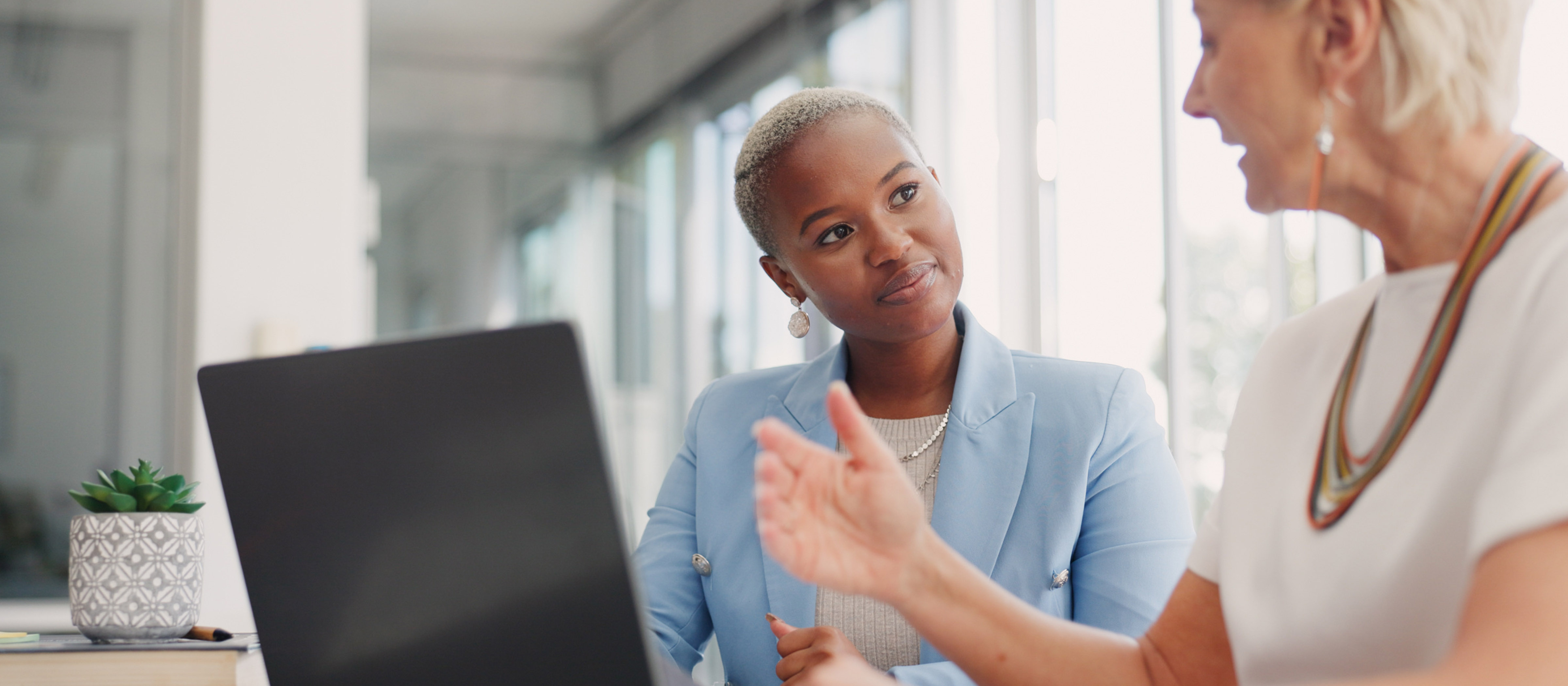 Two businesswomen talking near laptop