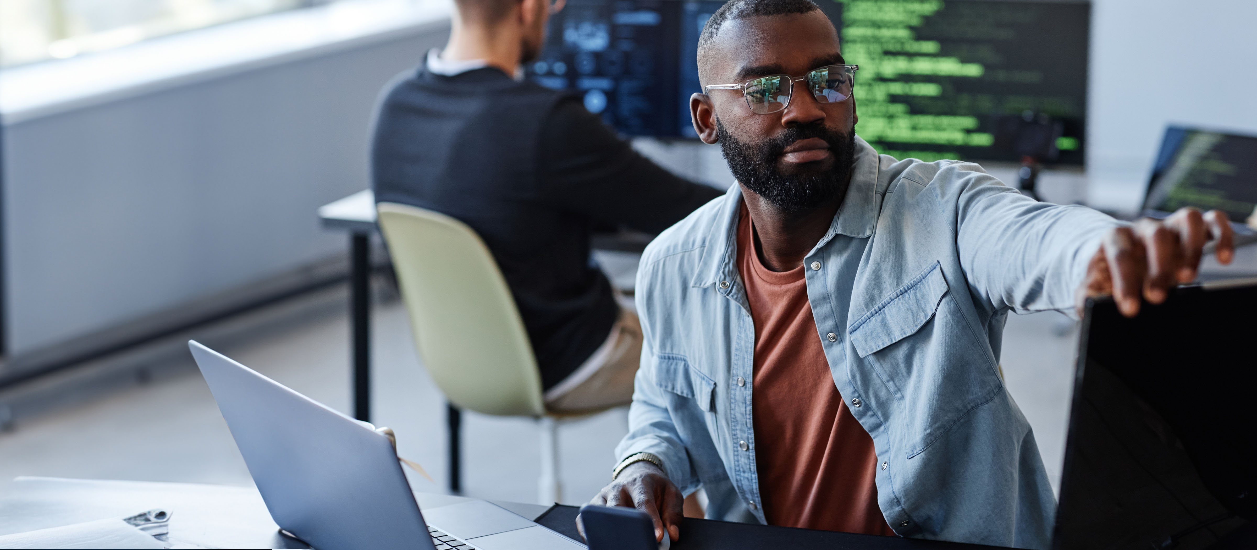 Man sitting at a desk looking at a computer monitor 