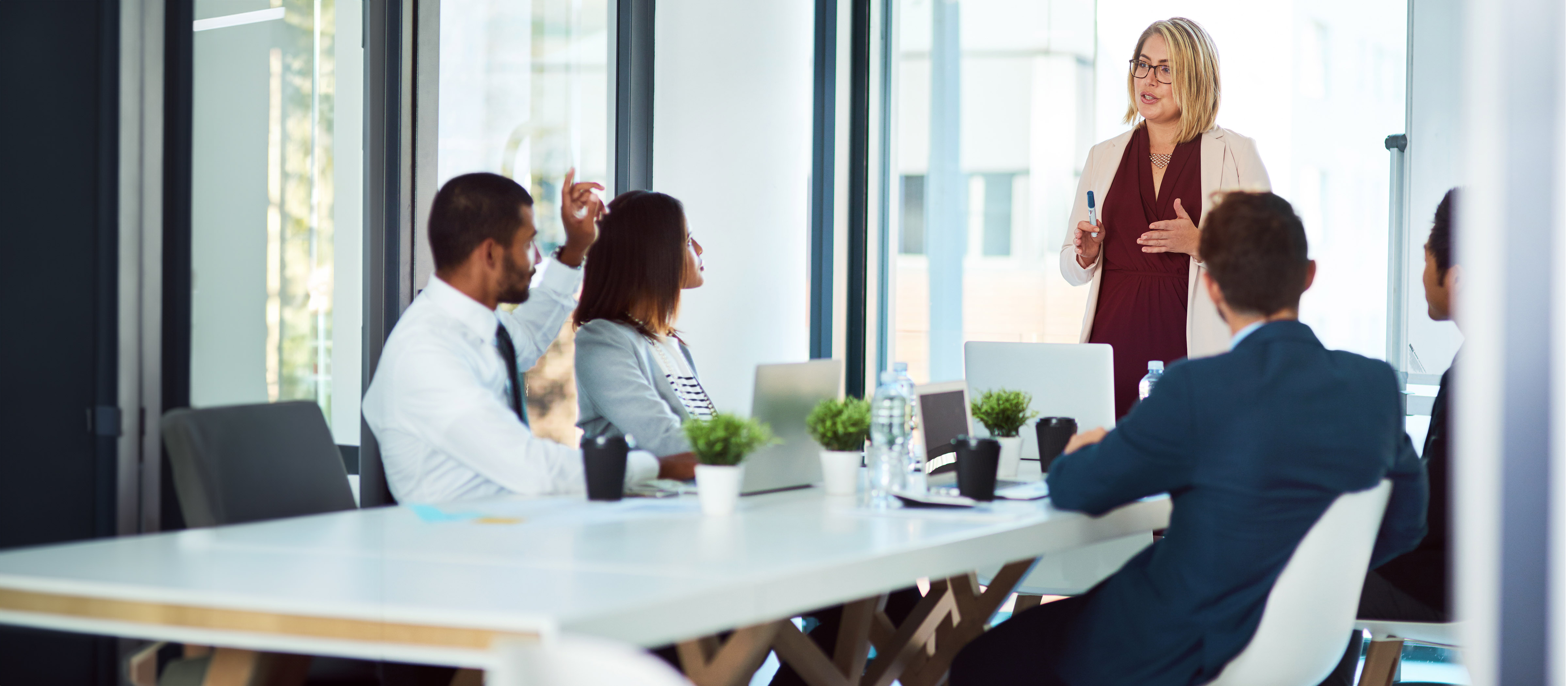 Woman speaking to a table of people in an office setting 