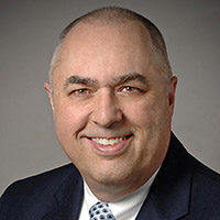 a headshot of a man wearing a suit jacket and tie