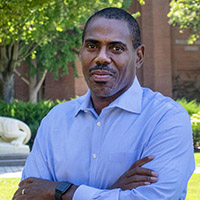 a headshot of a man with his arms crossed