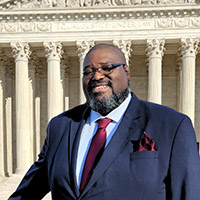 a man in a suit in front of a government building with columns