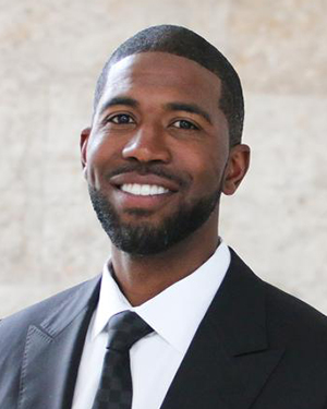 A man wearing a suit poses for a headshot photo.