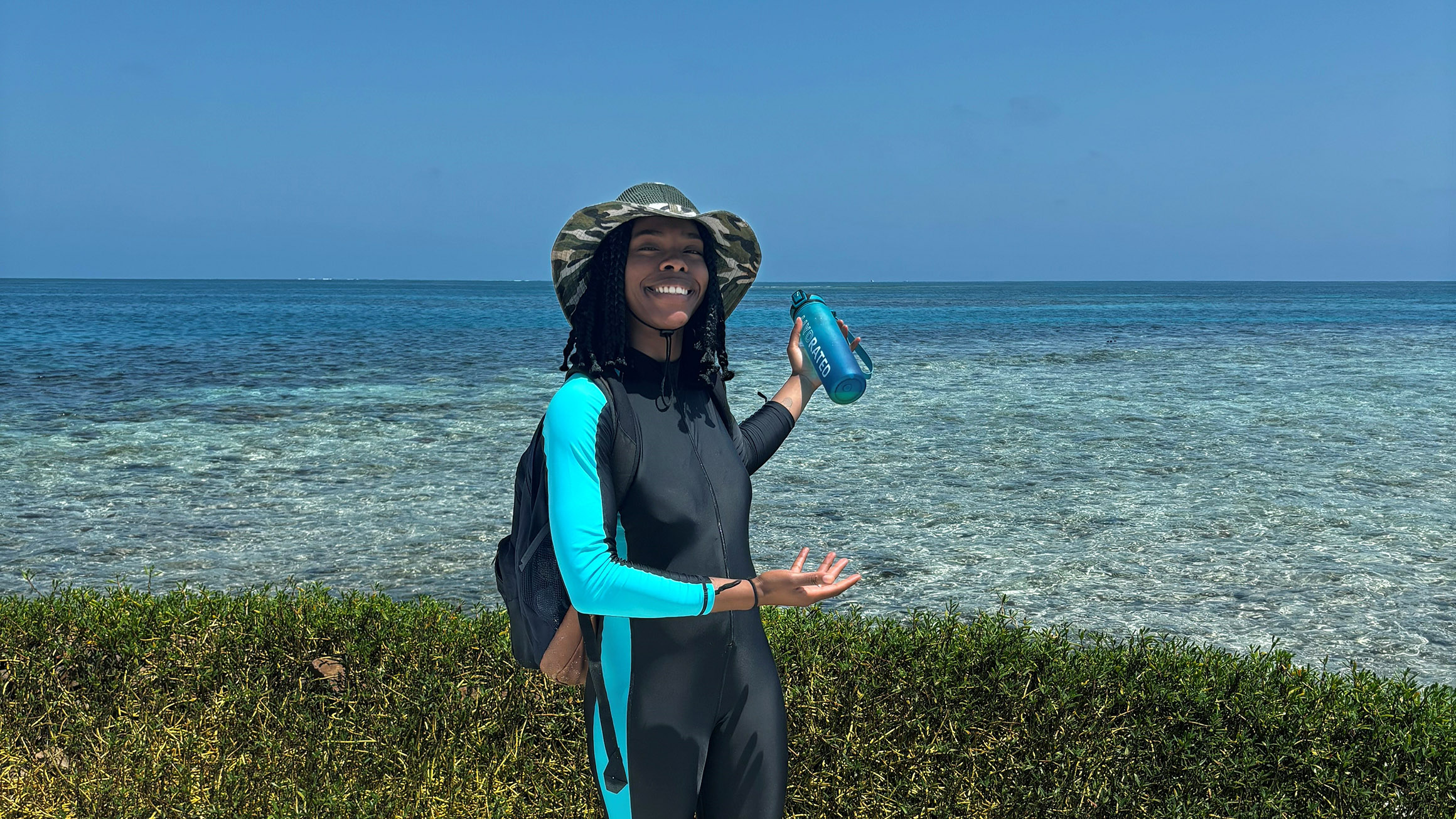 a woman pointing to the ocean with seaweed in the immediate background