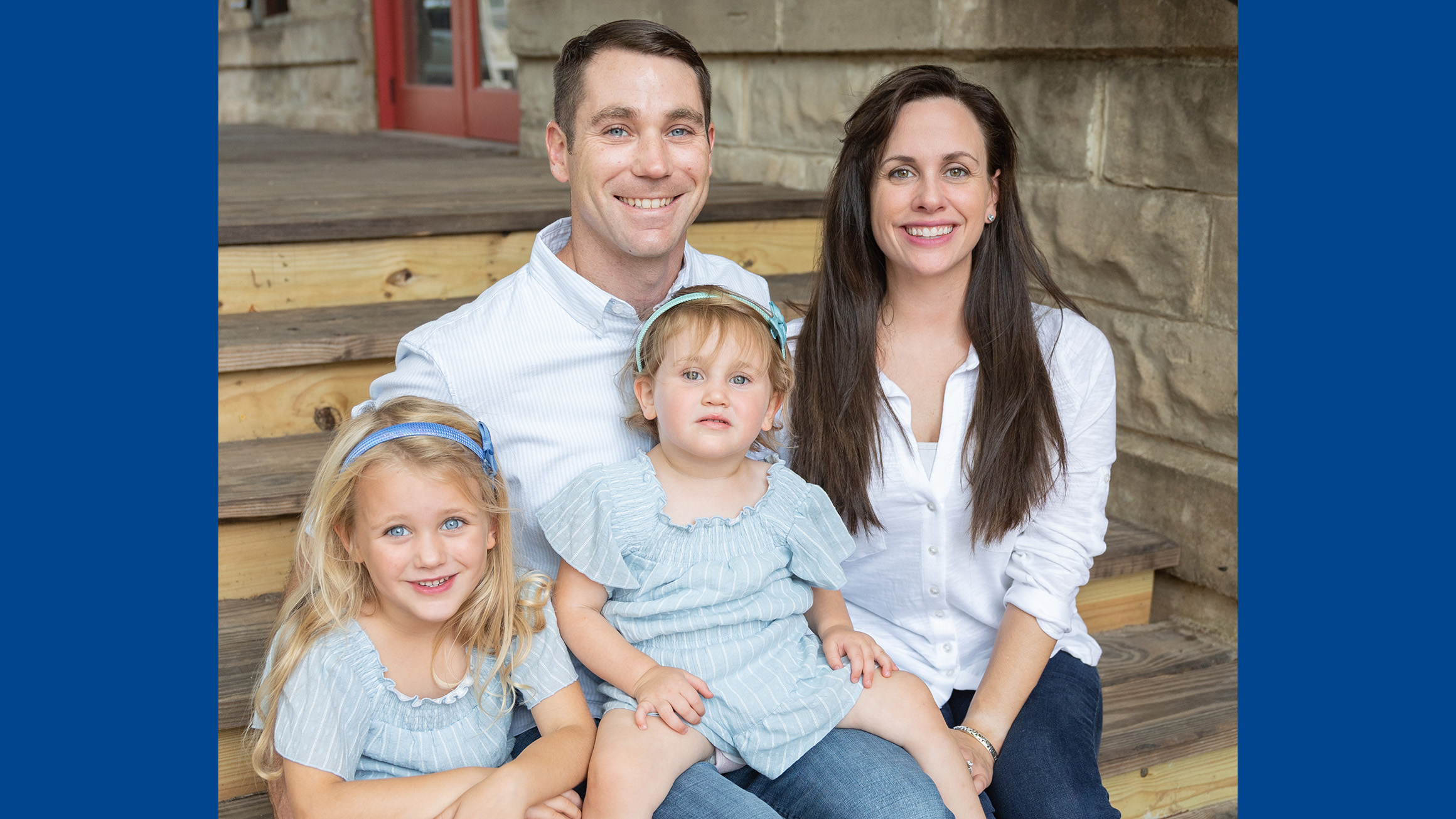 a man and a woman pose on steps with their two daughters
