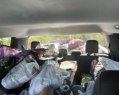 A passenger truck with piles of bags filled with pet supplies.