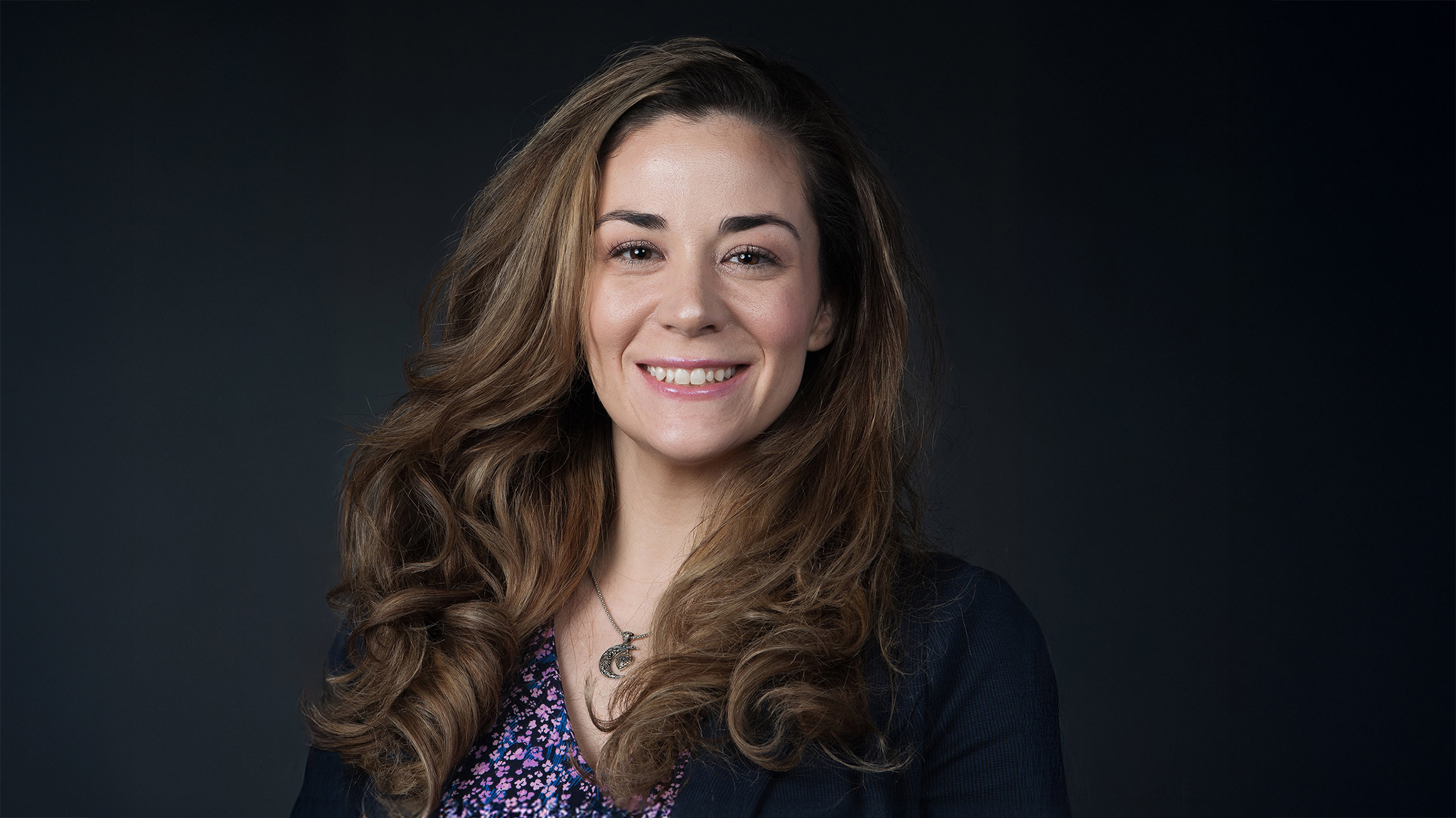 A headshot of a woman in front of a dark background.