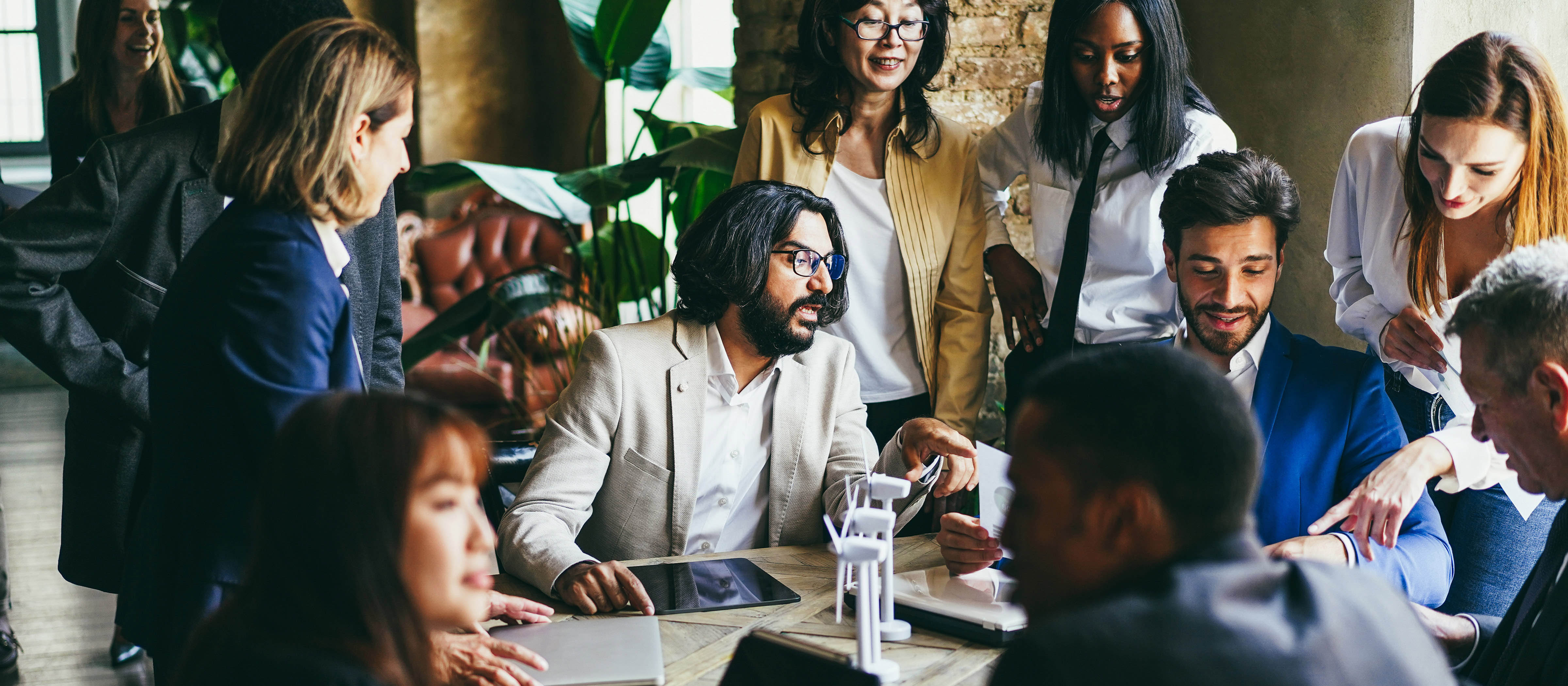 Group of men and women sit around a table discussing a project.