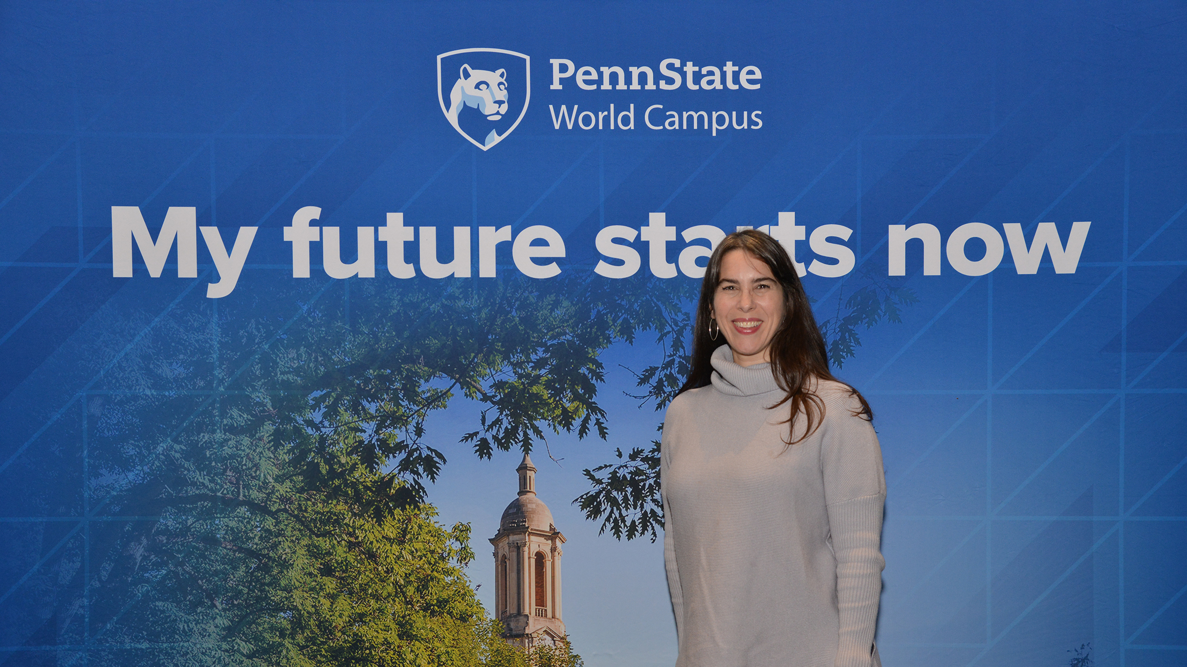 A woman stands in front of a Penn State–themed backdrop.