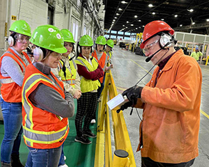 A group of people wearing reflective vests and hard hats in a factory.
