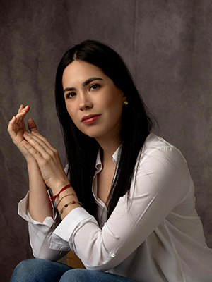 A woman wearing a white shirt sits for a professional headshot.