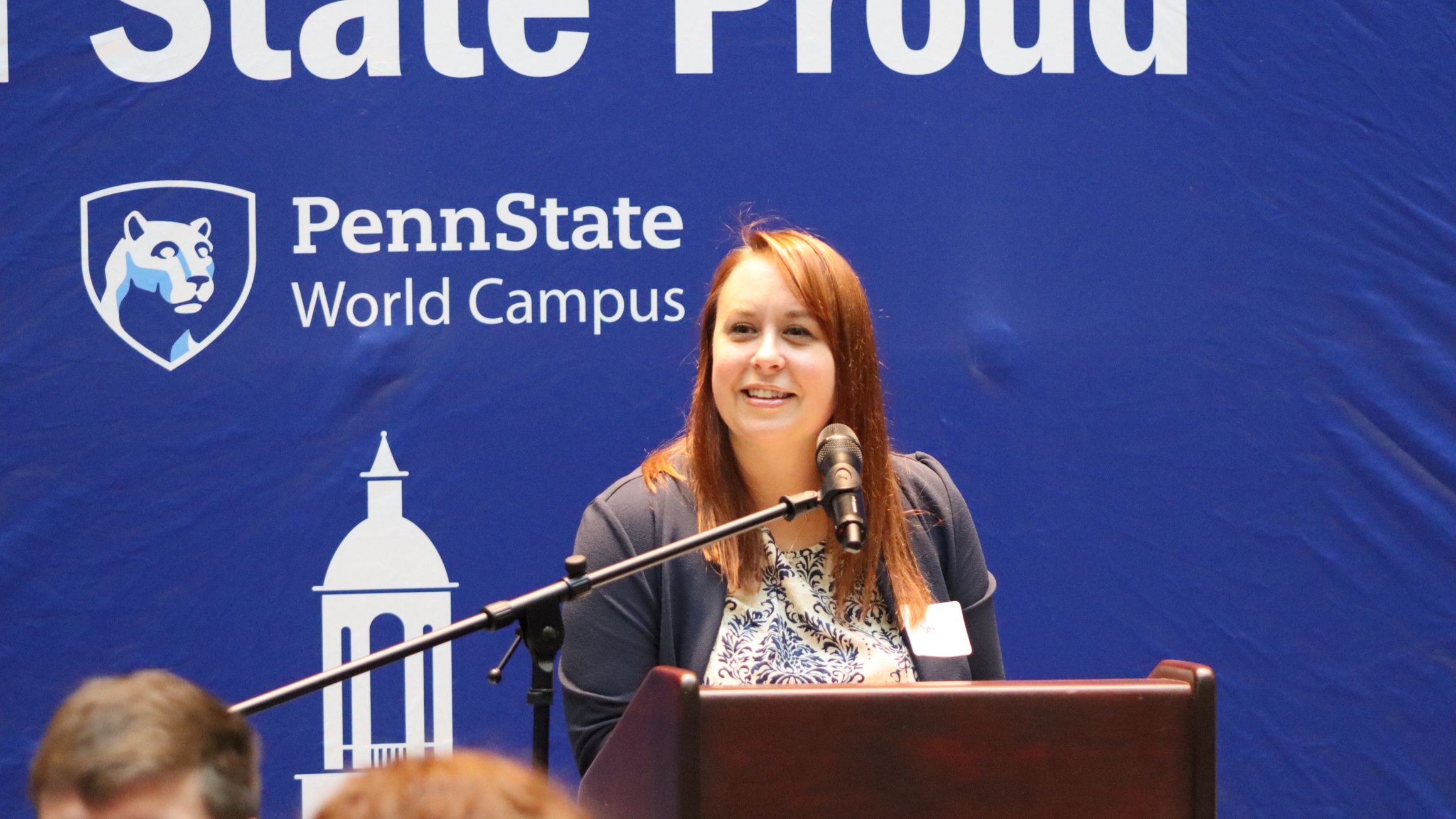 a woman stands at a podium announcing something