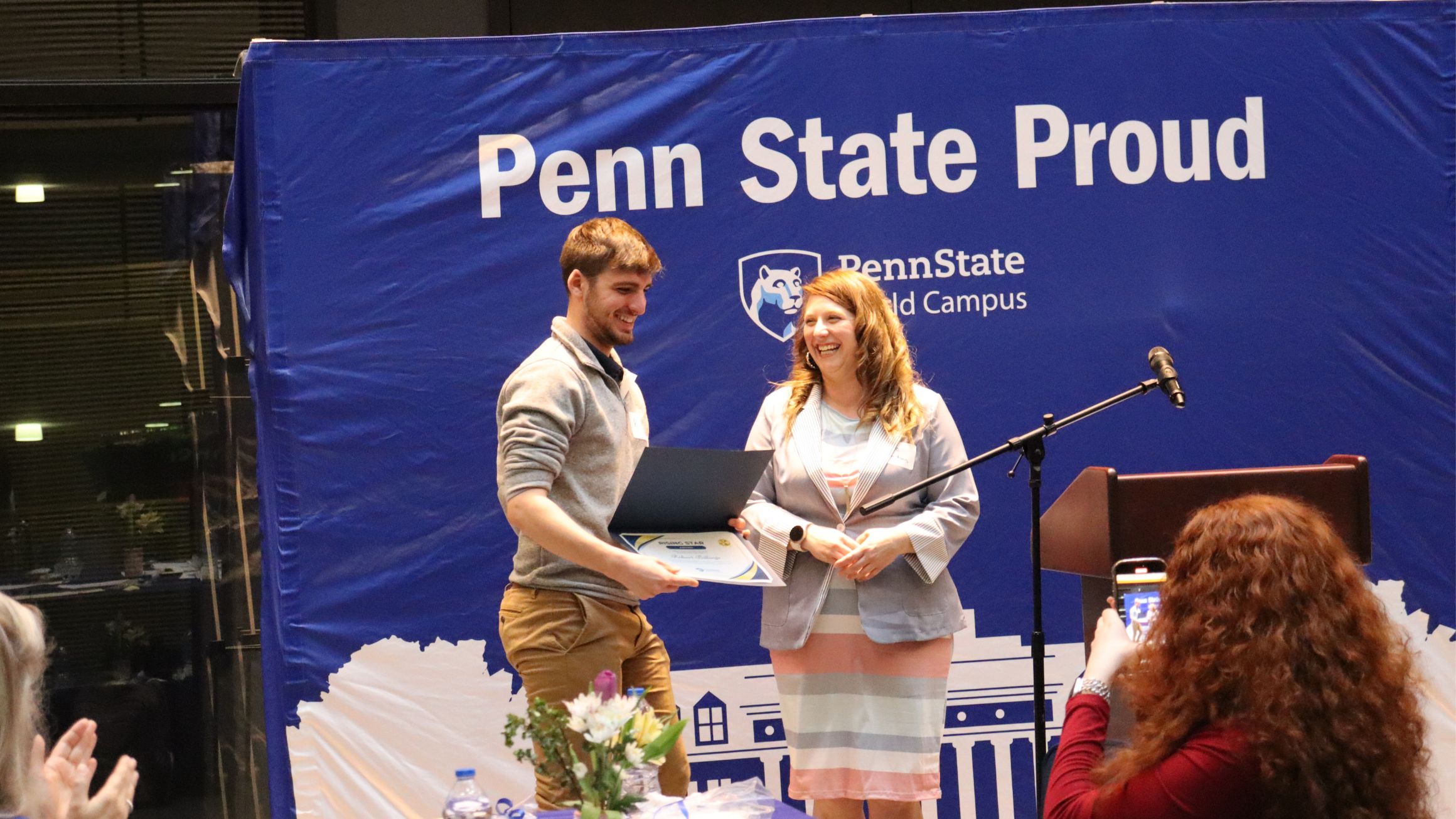 a man receives an award on a stage from a woman