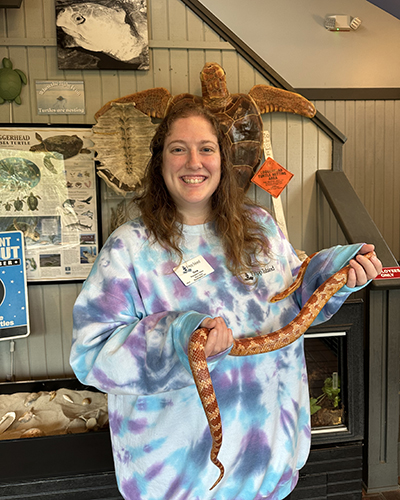 A woman holds a snake in a nature center.