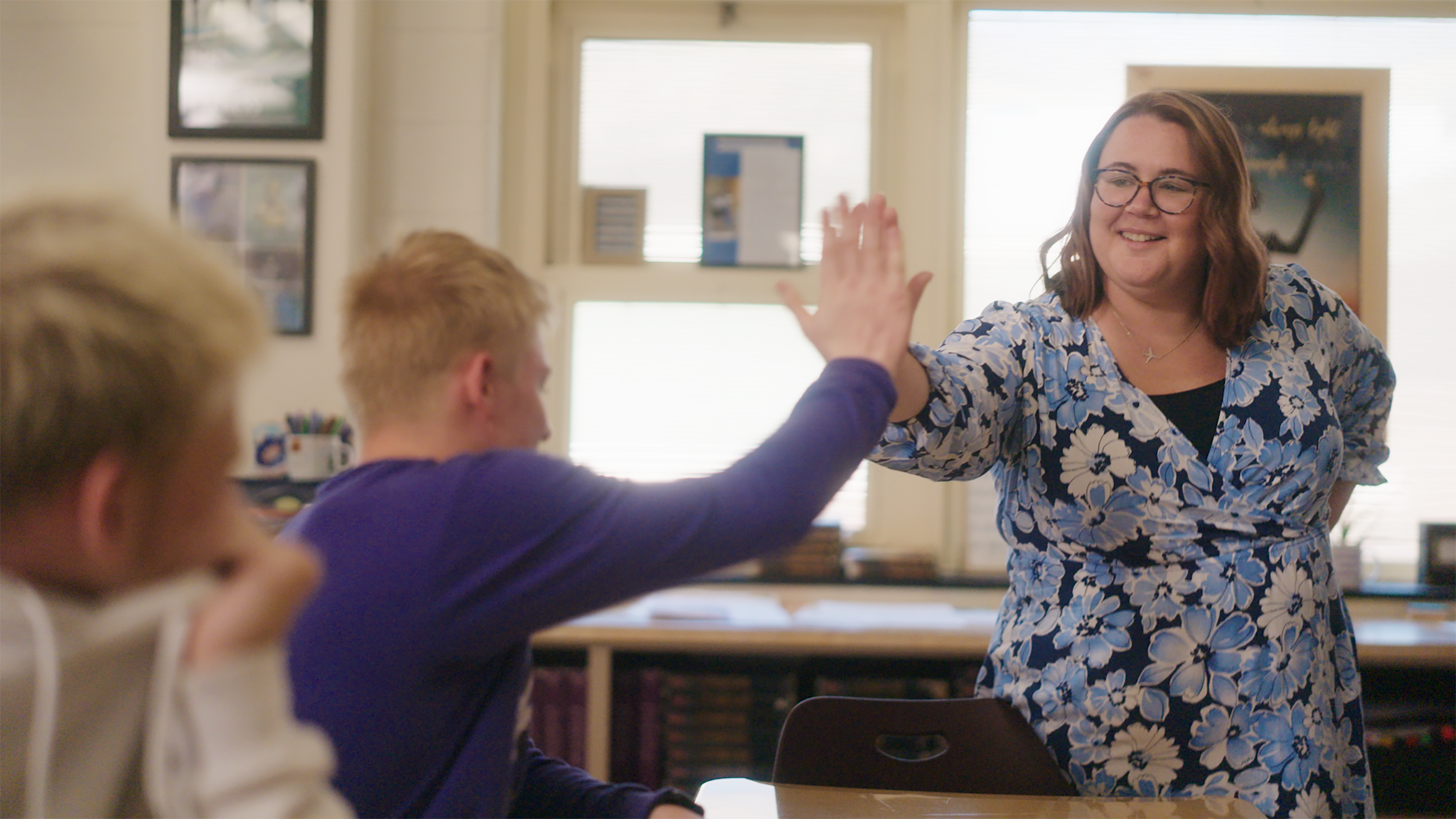 A woman high-fives a student.