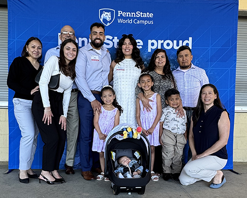 A group of adults and children pose in front of a blue background.