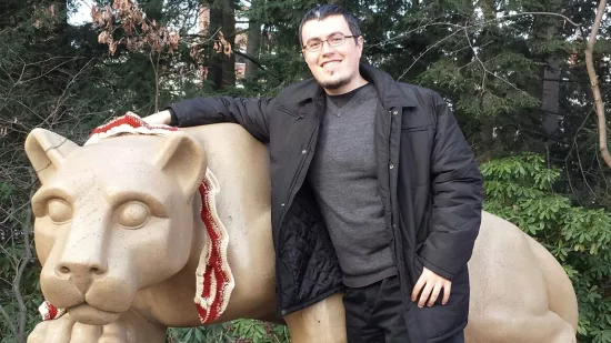 Ray Vasquez posing next to the Nittany Lion statue.