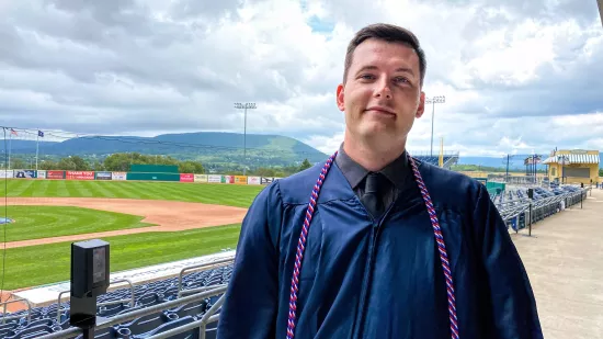 David Altier is seeing wearing a blue graduation gown with military cords.