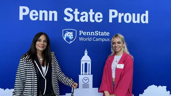 Nina Hatala and her mom pose for a photo behind a Penn State Proud banner.