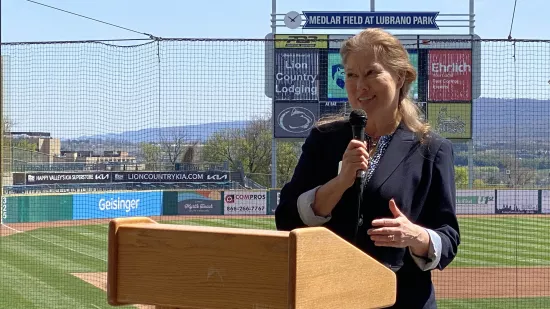 Renata Engel, the vice provost for Online Education at Penn State, addresses the Class of 2020 graduates from a podium with the diamond of a baseball field behind her.