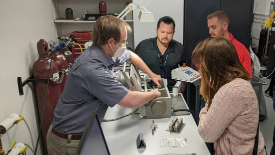 Four people work at a lab bench.