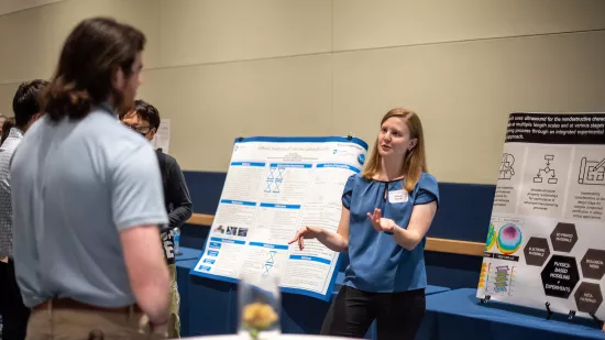 A woman presents information on a large poster.