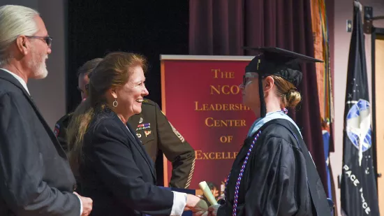 Maureen Meehan shakes hands with Renata Engel on a stage