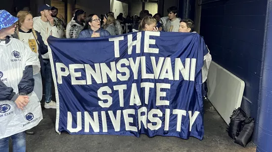 Students hold the Pennsylvania State University sign in the tunnel of Beaver Stadium before going out onto the field.
