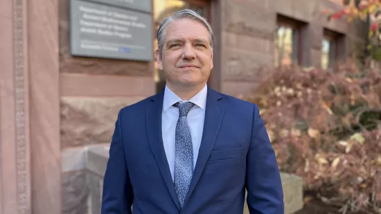 Christopher Lawrence stands in front of a building on campus