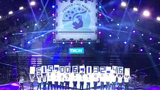 THON committee members hold signs revealing 2023's total, $15,006,132.46.
