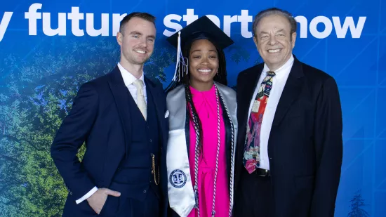 Three people pose in front of a blue background.