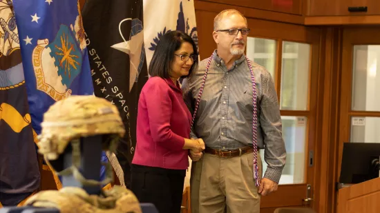 Two people shake hands and pose for a photo.