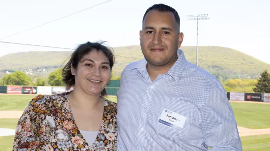 A man and woman pose in front of mountains.