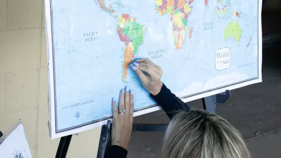 A woman pins a spot on a world map.