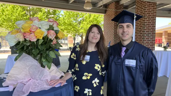 Yana Irwin stands with her advisee Nick Brown, who is wearing a graduation cap and gown.