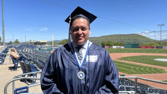 Yuri Morales in his graduation cap and gown with a medal around his neck.