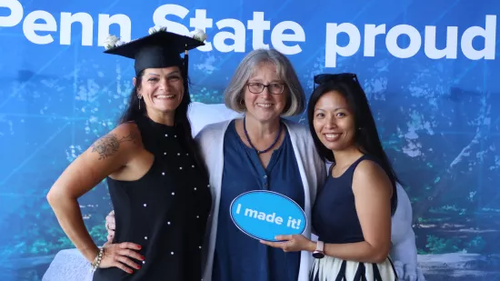 Three women pose together in front of a blue and white backdrop.