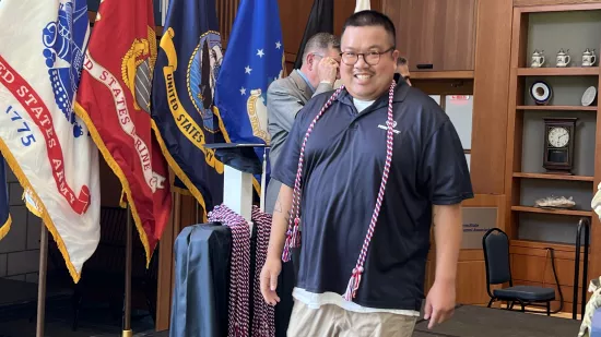 Mac Engstrand walks on the stage, wearing the honor cords around his neck