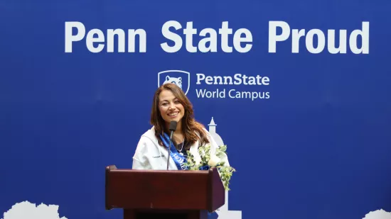 A woman stands in front of a Penn State-themed backdrop.