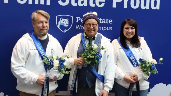 Three people pose in front of a blue background.