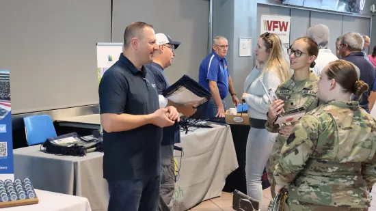 A man speaks to two women wearing camouflage uniforms.