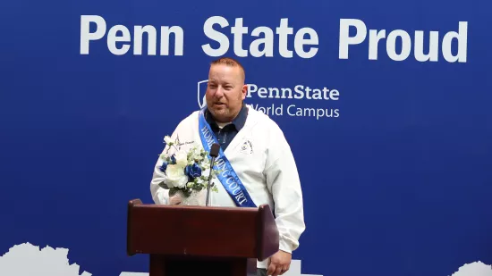 A man stands at a podium in front of a Penn State background.